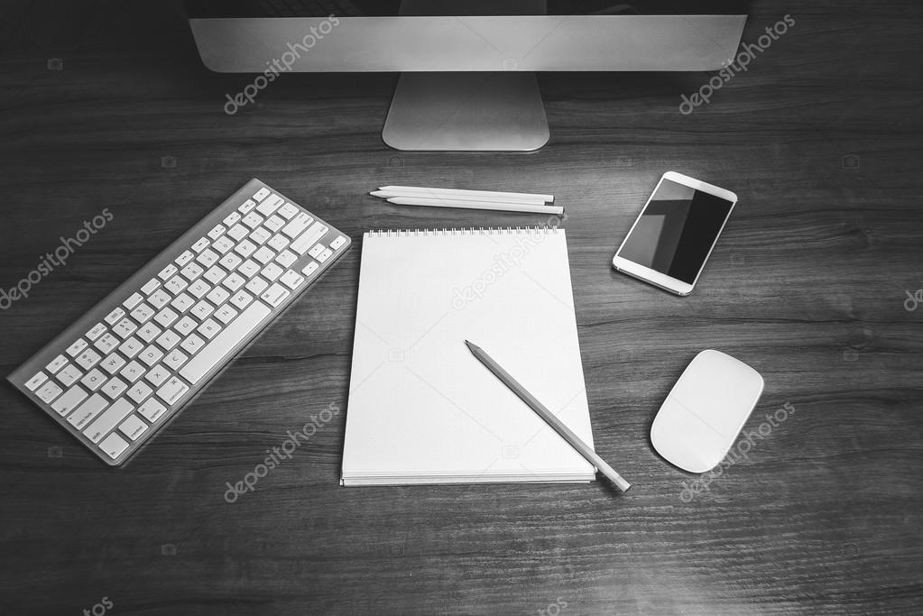Top view on a workplace with computer blank notepad pencils keyboard and mobile phone. Vintage, black and white vignetting and grain. Mock up