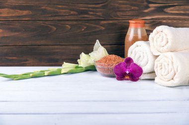 Spa havlu, scrubs ve deniz tuzu ile orkide beyaz tahta masada ortasında ayarla. Kopya alanı ile.