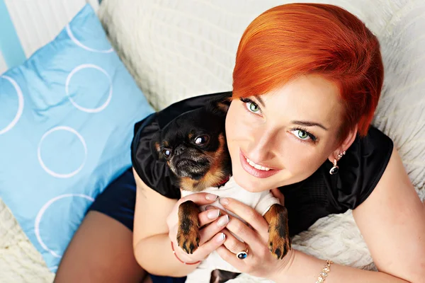 smiling beautiful young woman holds her dog in her arms