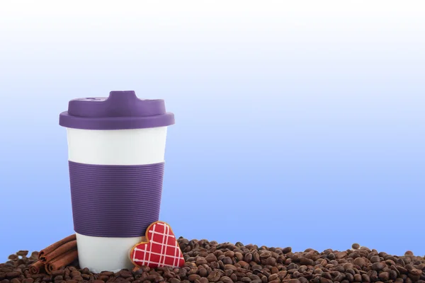Takeaway ceramic cup and coffee beans on blue background
