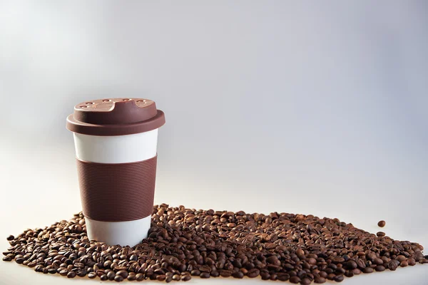 Taça de cerâmica Takeaway e grãos de café no fundo azul — Fotografia de Stock