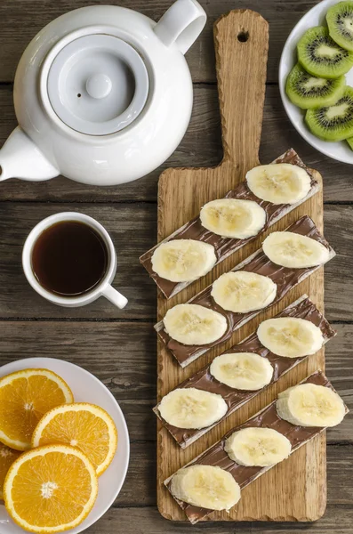 Frukost kex med choklad pasta och bananer, kaffe och frukt — Stockfoto