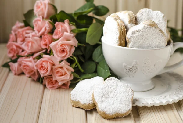 Galletas españolas para la grasa en una taza con un ramo de rosas — Foto de Stock