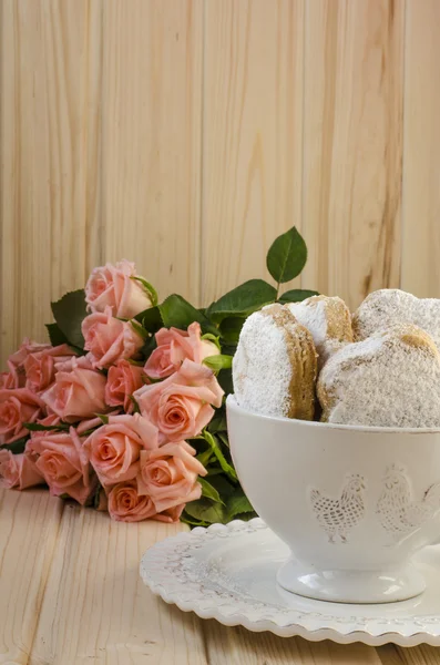 Spanische Kekse für Fett in einer Tasse mit einem Rosenstrauß — Stockfoto