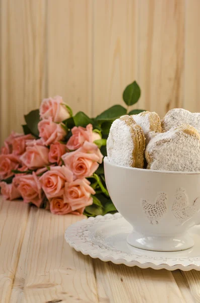 Galletas españolas para la grasa en una taza con un ramo de rosas — Foto de Stock