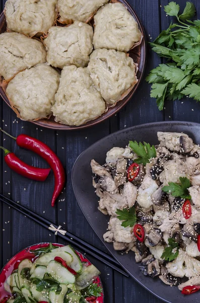 Lunch i asiatisk stil kinesisk ångad bullar, Gurksallad och kokt kyckling, svamp och blomkål i en sås med chili och örter — Stockfoto