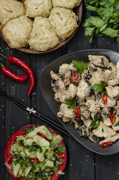 Lunch in the Asian style Chinese steamed buns, cucumber salad and steamed chicken, mushrooms and cauliflower in a sauce with chilli and herbs — Stock Photo, Image