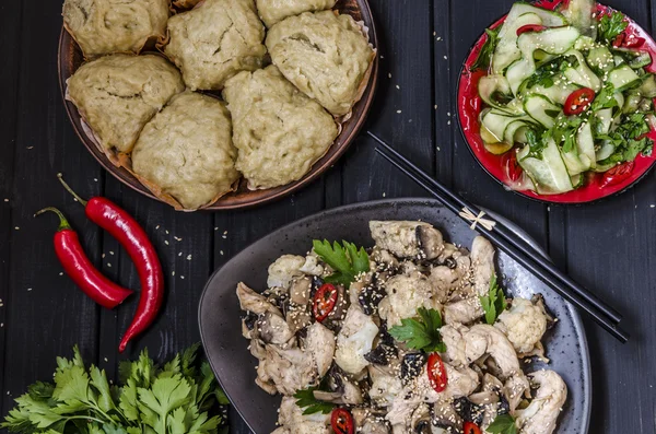 Lunch in the Asian style Chinese steamed buns, cucumber salad and steamed chicken, mushrooms and cauliflower in a sauce with chilli and herbs — Stock Photo, Image