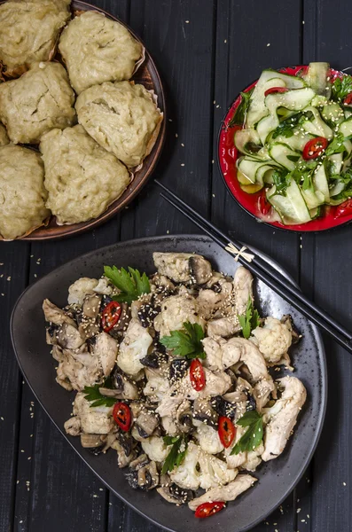 Lunch in the Asian style Chinese steamed buns, cucumber salad and steamed chicken, mushrooms and cauliflower in a sauce with chilli and herbs — Stock Photo, Image