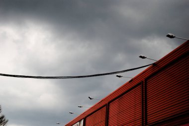 Alışveriş merkezi duvarı ve fırtınalı gökyüzüne karşı sokak lambaları