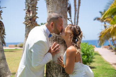 Parkta damat ve gelin öpüşüyor, yeni evli çiftler inanılmaz güneşli bir günde düğün öpüşmelerini kutluyorlar..