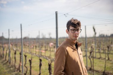 Genç bir çiftçi üzüm bağında poz verir.