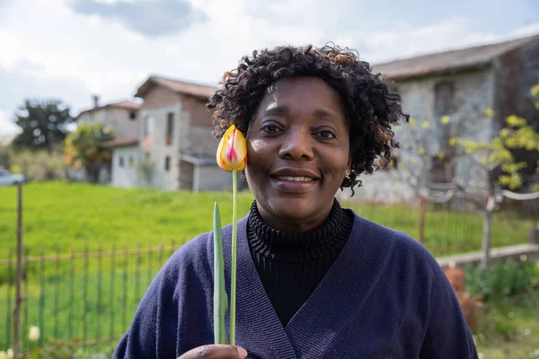 Portret Pięknej Afroamerykanki Średnim Wieku Uśmiechniętej Trzymającej Żółtego Tulipana Blisko — Zdjęcie stockowe