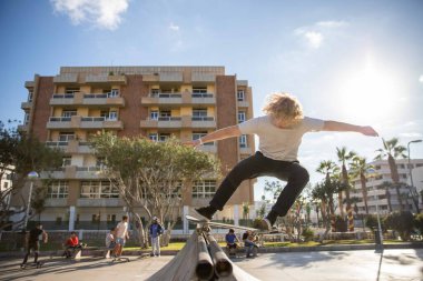 Çocuk kaykayıyla parktaki rampada eğleniyor.