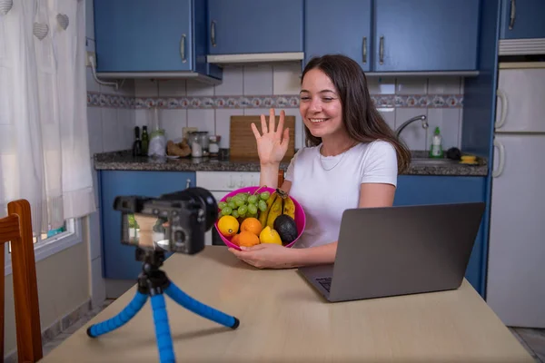 Young female blogger films herself with a basket fruit. Beautiful influencer woman creates content for her social networks, Healthy lifestyle concept. Smiling girl.