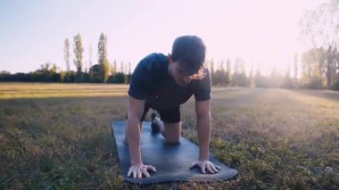 Childs 'ta gerinen bir adam halka açık bir parkta yoga pozu veriyor.