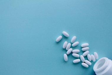 Mavi arka planda bir sürü hap şişeden dökülüyor. Fotokopi alanı. Tıp konsepti