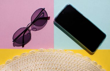 Arka planda gezgin aksesuarlarıyla yatıyordu. Güneş gözlüğü, akıllı telefon ve şapka. Seyahat arka planı, Top view. Yaz tatili kavramı