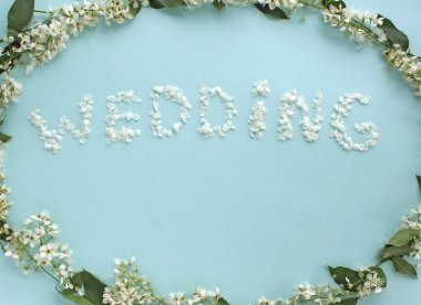Beyaz çiçeklerle çerçevelenmiş mavi bir zemin üzerinde yazılı düğün