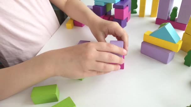 Close-up of a childs hand playing with wooden colored cubes on a white windowsill at home. — стоковое видео