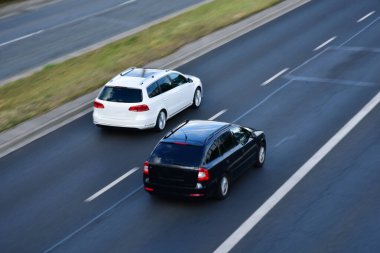 İki siyah beyaz araba otoyolda ilerliyor, üst görüş, yüksek hız trafiği, yarış, uzun pozlama, hızlı hareket etkisi.