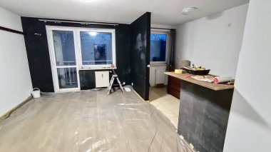Tamamlanmamış bir apartman dairesinin duvarını ve hücresini boyuyor. Ev yenileme, yenileme, inşaat ve emlak geliştirme konsepti.