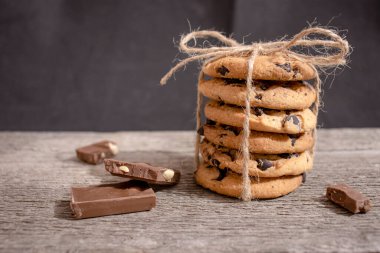 Çukulatalı kurabiyeler, sicimle bağlanmış çikolata parçaları ve yakın plan ahşap bir fonda çikolata parçaları.