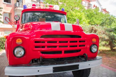 Çok katlı bir binanın arka planında kırmızı itfaiye aracı var.