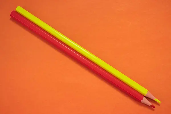 Czerwone Żółte Ołówki Leżące Pomarańczowym Tle Zbliżenie — Zdjęcie stockowe