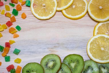 Çok renkli meyveler, limon dilimleri ve ahşap bir arka planda kivi.