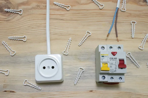 Electrical outlet, automatic electrical switch, plastic wire fasteners and residual current device on a wooden background close-up