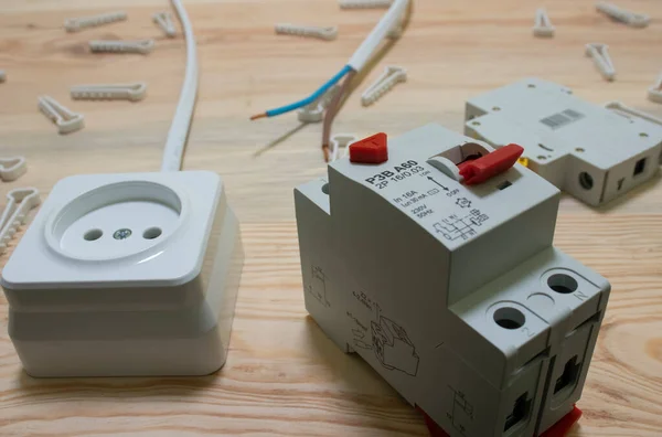 Elektrik prizi, otomatik elektrik anahtarı, plastik tel bağlayıcılar ve ahşap arka plandaki artık akım cihazı.