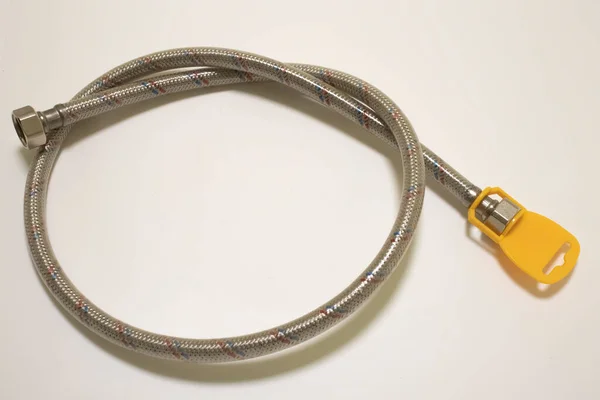 Metal plumbing hose with tag on white background close up