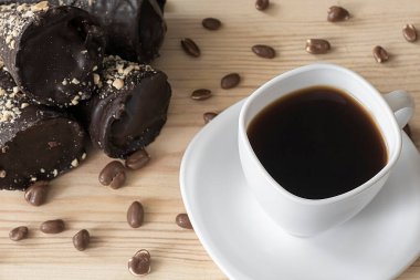 Beyaz kahve, çikolata tüpleri ve çikolatalı fıstıklar ahşap masanın üstünde.