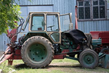 Büyük bir Belarus traktörü. Ön ve arka kovası var. Açık havayı kapatın.