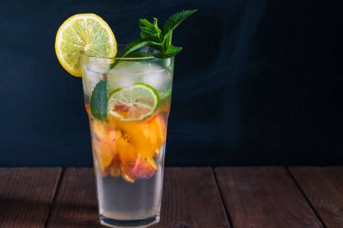 Şeftalili mojito şeffaf bardakta, buzlu, koyu arkaplanda.