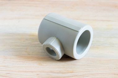 Farklı çaplardaki polipropilen borularını ahşap bir arka planda birbirine bağlamak için T harfi