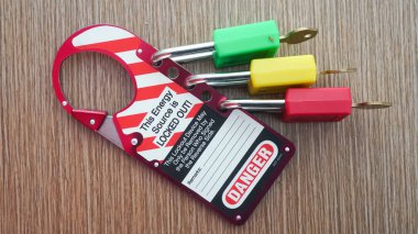 Three keys are red, yellow, green. Lock Out, Tag Out with danger sign. Electrical systems and machinery and safety equipment. There is a Danger warning and Don't Delete. Install the Lock. clipart