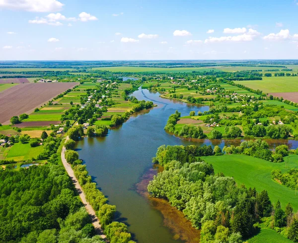 Top view aerial shot of green field and blue river in the summer. Beautiful landscape from the sky. The river is divided into two streams. Lots of green fields and trees. Bird\'s eye on top. Spring nature in the meadows. Top view drone shot of a green