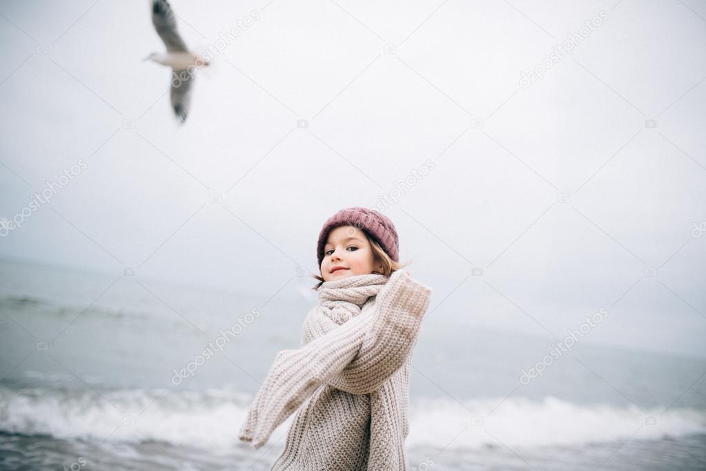 Girl in warm clothes at the beach