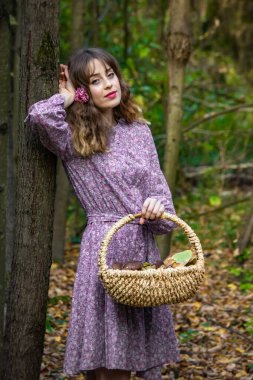 Çiçek desenli ve içi mantar dolu bir elbiseyle ormanda bir kız. Fotoğraf eski stilde.