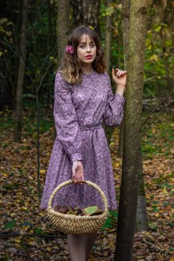 Çiçek desenli ve içi mantar dolu bir elbiseyle ormanda bir kız. Fotoğraf eski stilde.