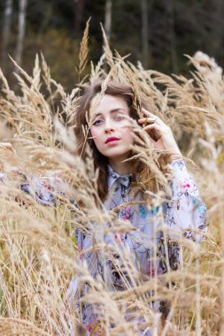 Karanlık bir ormanın arka planında otların arasında kurumuş güzel bir kız. Buğdayla kaplı elbiseli bir kadın.