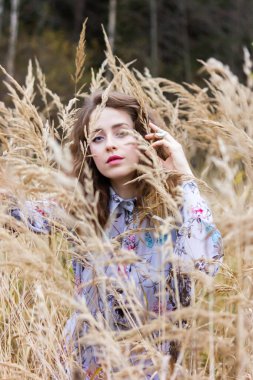 Karanlık bir ormanın arka planında otların arasında kurumuş güzel bir kız. Buğdayla kaplı elbiseli bir kadın.