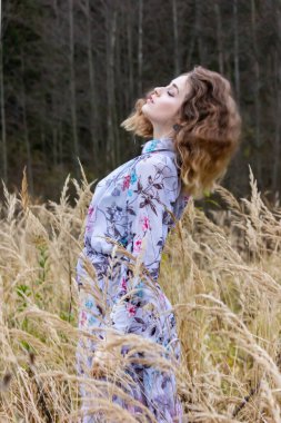 Karanlık bir ormanın arka planında otların arasında kurumuş güzel bir kız. Buğdayla kaplı elbiseli bir kadın.