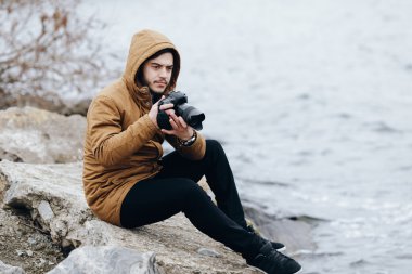 Nehir kıyısında oturan kamera ile fotoğrafçı