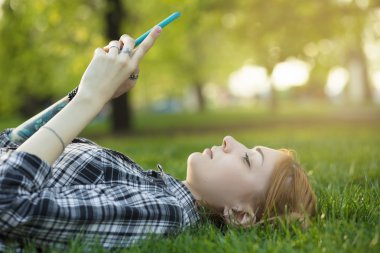 çimenlerin üzerinde akıllı telefon kullanan kadın