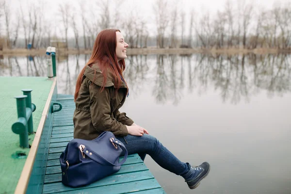 Jonge vrouw zittend op de pier — Stockfoto