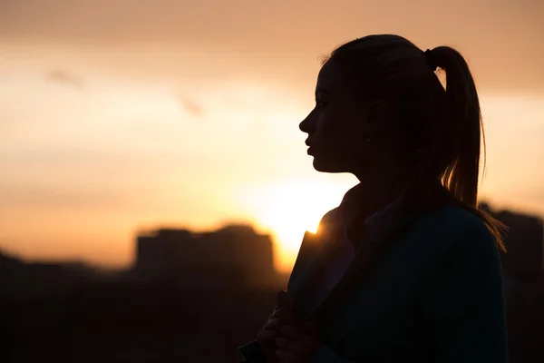 Silhouette femminile sopra la città del tramonto — Foto Stock