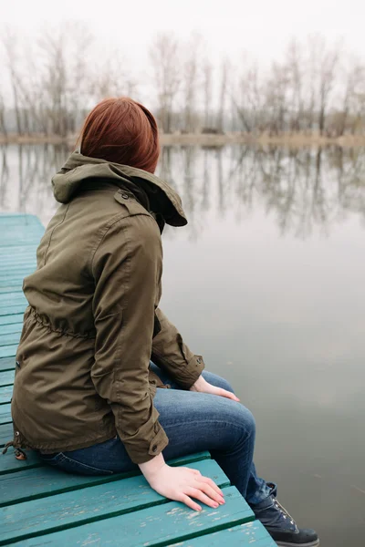 Frau sitzt auf Seebrücke — Stockfoto